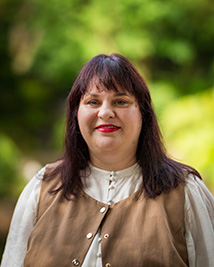 Infinity Community Services Ltd. General Manager of Client Services for South Australia Angela DeConno stands looking into the camera. She has shoulder length straight hair, is wearing a white shirt with a camel coloured vest. 